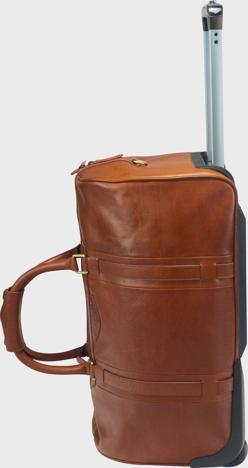 Side view of a tan Rawlings Home Run wheeled duffle bag standing up with the telescoping handle extended out