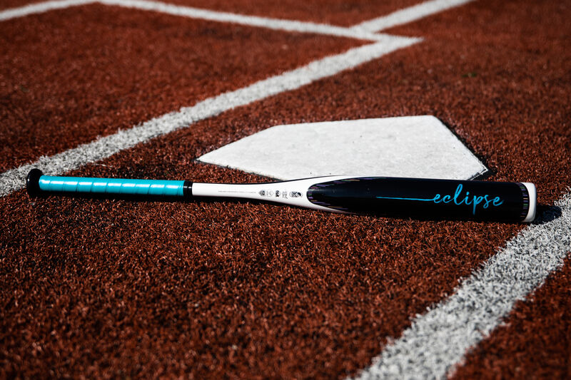 A Rawlings Eclipse fastpitch bat lying on a field next to home plate - SKU: FPZE12 loading=