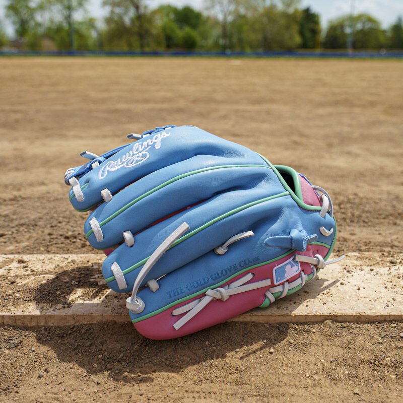 Picture of the back of a columbia blue/pink Exclusive Rawlings NXT Series 11.5" Infield Glove on a pitching rubber loading=