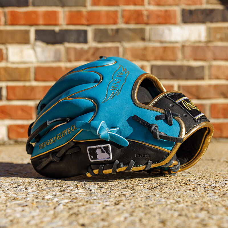 Picture of the pinky side of a teal/black Exclusive 11.5" Rawlings R2G Heart of the Hide infield glove in front of a brick wall