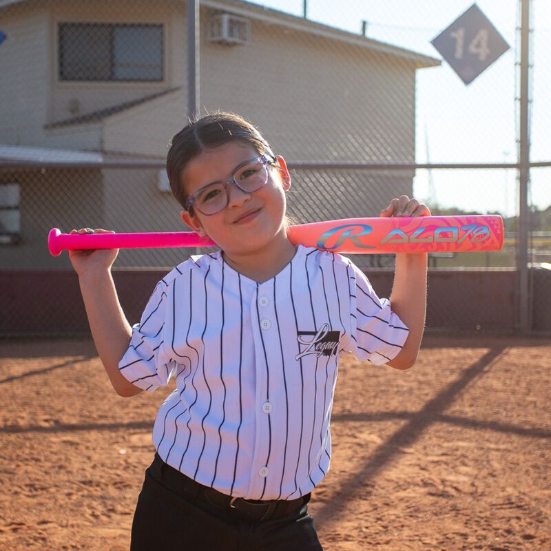 A girl holding a pink Rawlings ALO78 -12 fastpitch softball bat behind her head