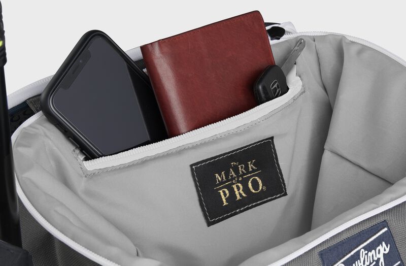 Zippered pocket in the top storage compartment of a navy Impulse backpack with a phone, wallet and keys - SKU: IMPLSE-N