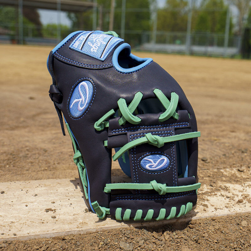 Picture of a navy exclusive Rawlings NXT Series 11.5" infield glove standing on its fingertips on a pitching rubber loading=