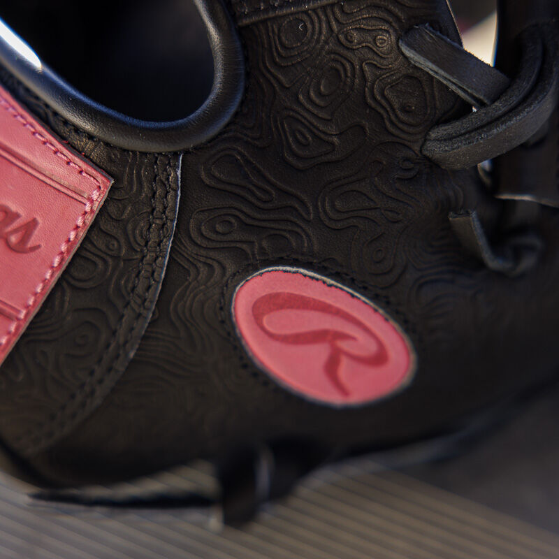 Picture of the pink leather Oval-R on the thumb of a black Rawlings R2G Heart of the Hide 11.5" glove