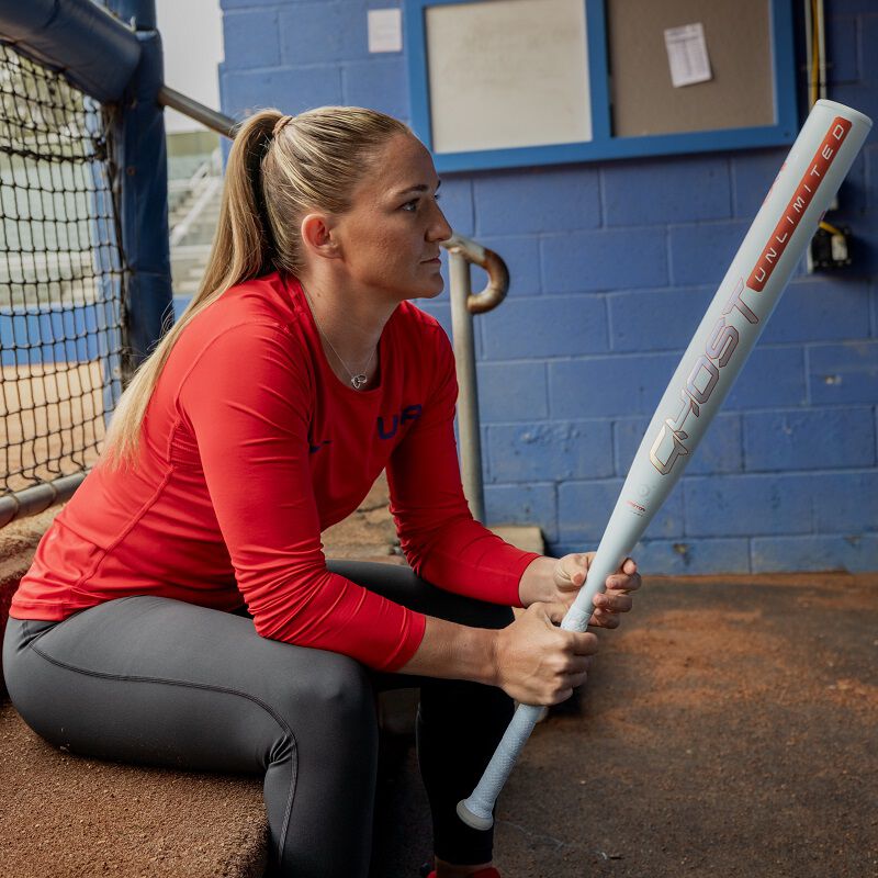 A picture of Haylie McCleney sitting in a dugout holding a Ghost Unlimited bat