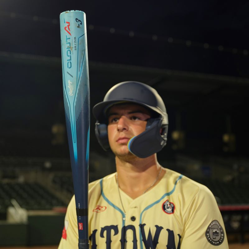 A player on a field holding and looking at the barrel of a Clout AI BBCOR bat loading=