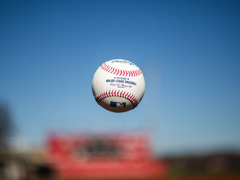 A Rawlings Major League baseball tossed in the air with the sky in the background - SKU: ROMLB loading=