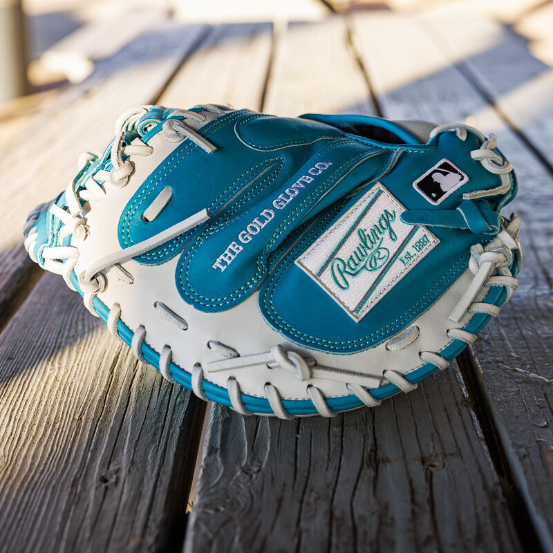 Picture of the back of a teal/white exclusive 33" Rawlings R2G Heart of the Hide catcher's mitt on a wood table