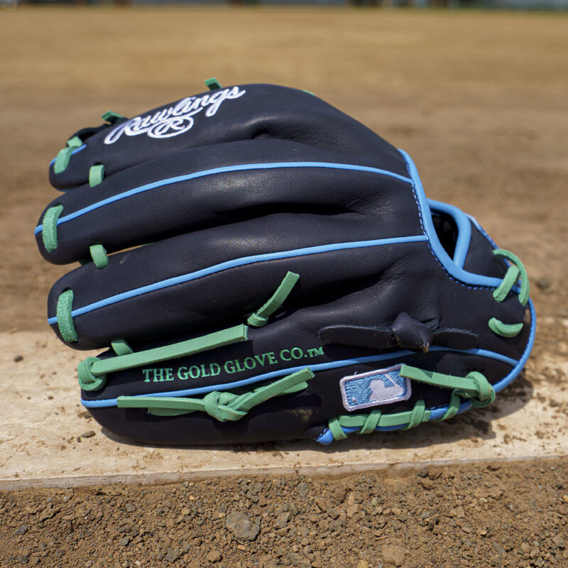 Picture of the back of a navy exclusive Rawlings NXT Series 11.5" infield glove on a pitching rubber loading=