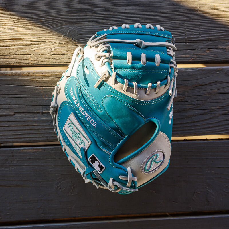 Picture from above of a teal/white exclusive 33" Rawlings R2G Heart of the Hide catcher's mitt on a wood table