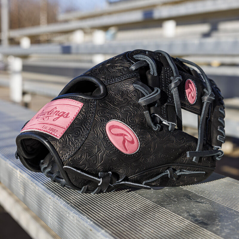 Picture of a black/pink Rawlings R2G Heart of the Hide 11.5" glove on a bench