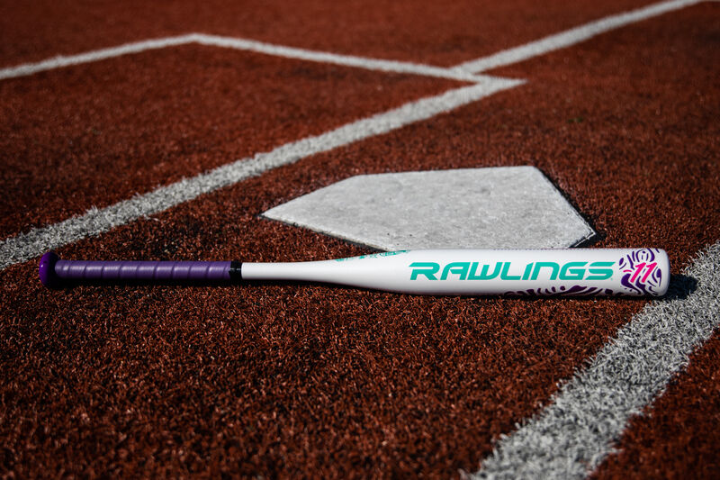 A Rawlings Ombre fastpitch softball bat lying on a field next to home plate - SKU: FPZO11 loading=