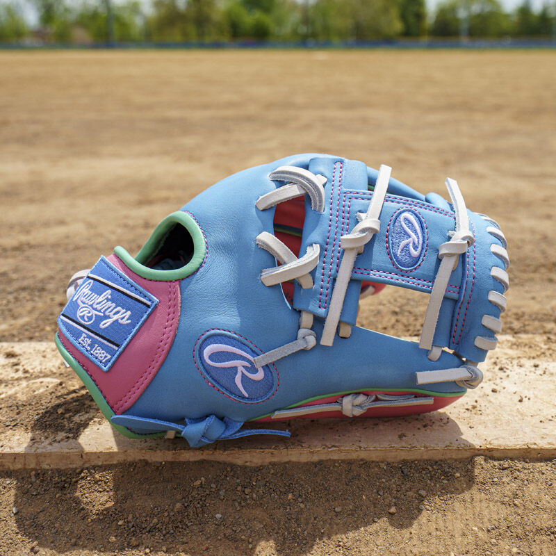 Picture of a columbia blue/pink Exclusive Rawlings NXT Series 11.5" Infield Glove on top of a pitching rubber loading=