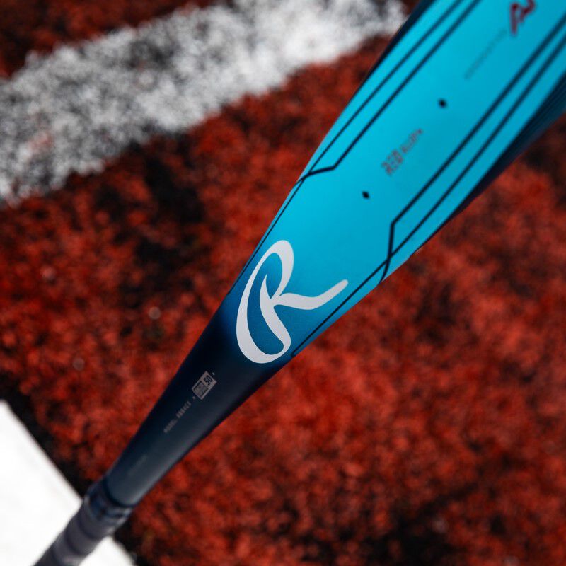 White "R" Rawlings logo on a blue Clout AI BBCOR bat with a field in the background loading=